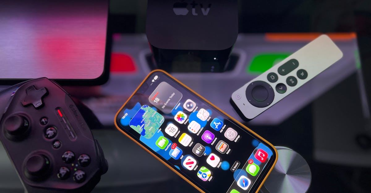Stylish home entertainment setup featuring an iPhone, Apple TV, and gaming controller on a dark surface.