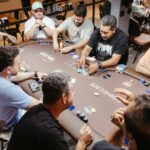 Group of men engaged in a poker game at an indoor setting, showcasing social interaction.