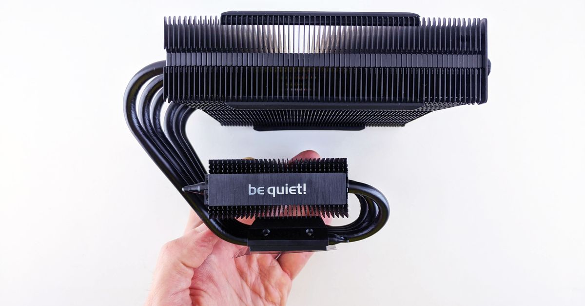 Close-up of a CPU cooler with a 'be quiet!' logo held in hand against a white background.