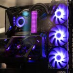 Modern gaming computer with vibrant LED fans and sleek glass design, showcasing high-performance components.