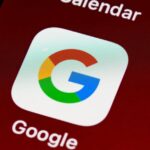 Macro view of a smartphone displaying Google and other app icons on the home screen.