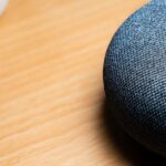 A close-up view of a smart speaker on a wooden table, capturing texture details.