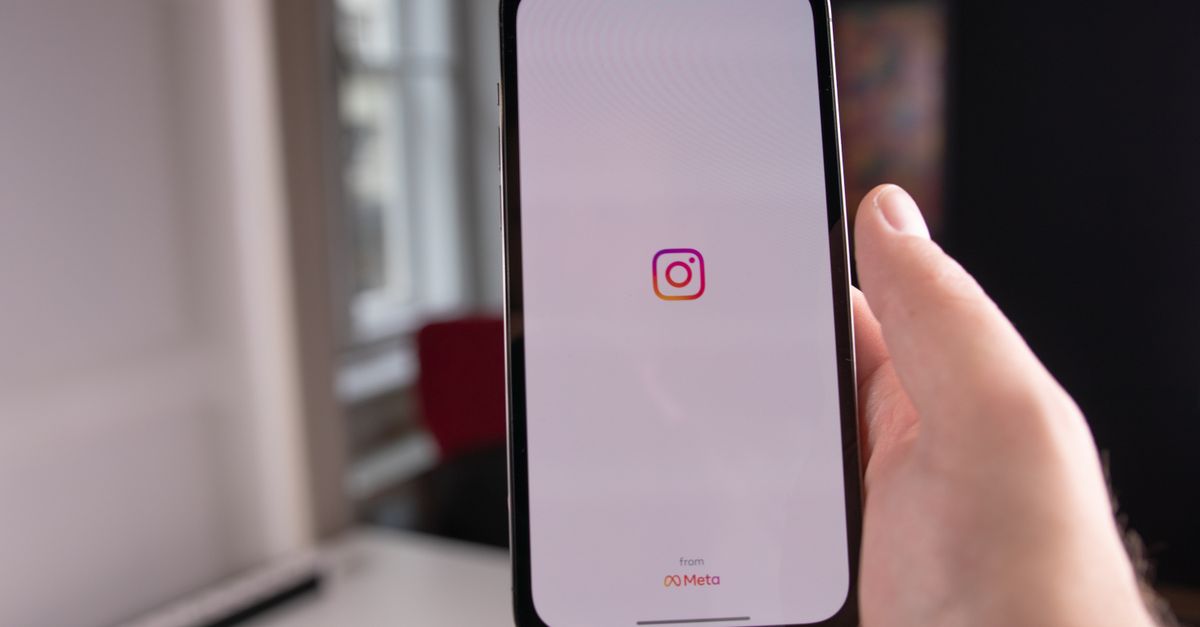 Close-up of a hand holding a smartphone displaying the Instagram app, indoors in Budapest.