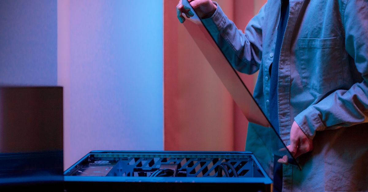A man carefully fits a glass panel onto a gaming PC while adjusting internal cables.