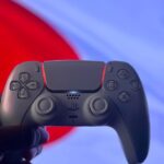 A PlayStation 5 DualSense controller is held up against a backdrop of the Japanese flag.
