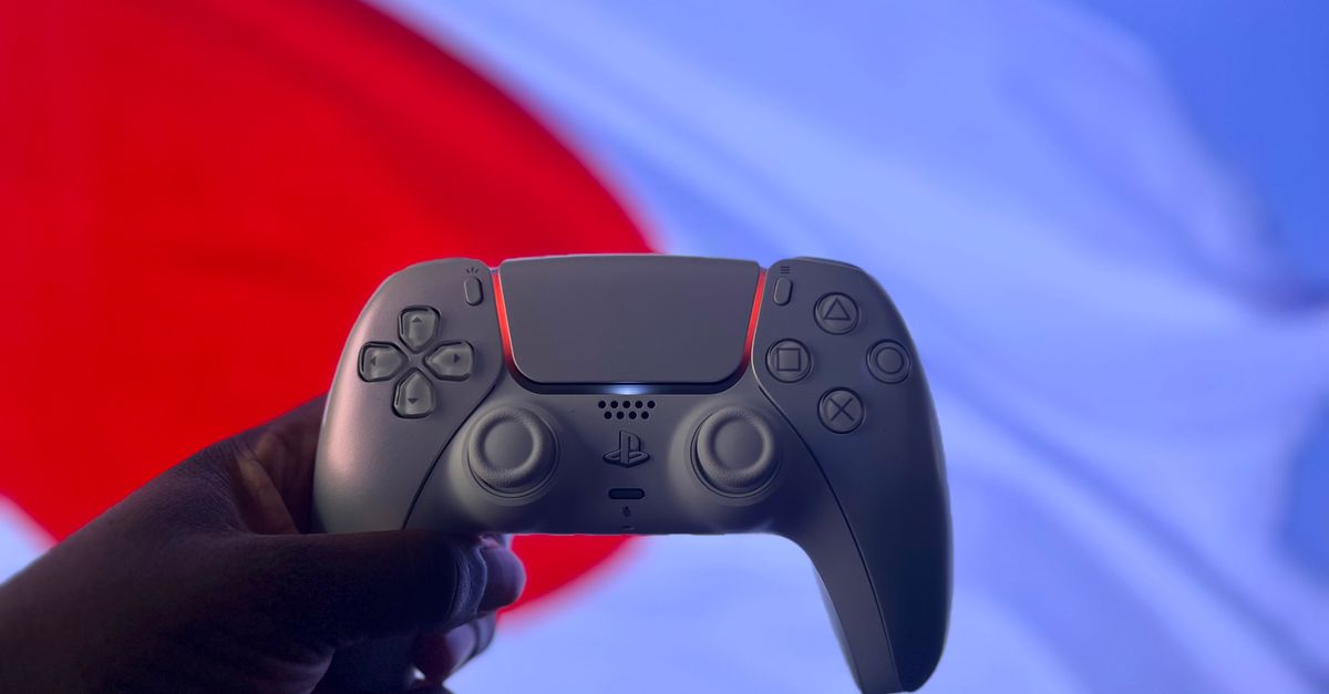 A PlayStation 5 DualSense controller is held up against a backdrop of the Japanese flag.