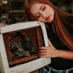 A woman embraces a vintage broken monitor, evoking nostalgia and style.