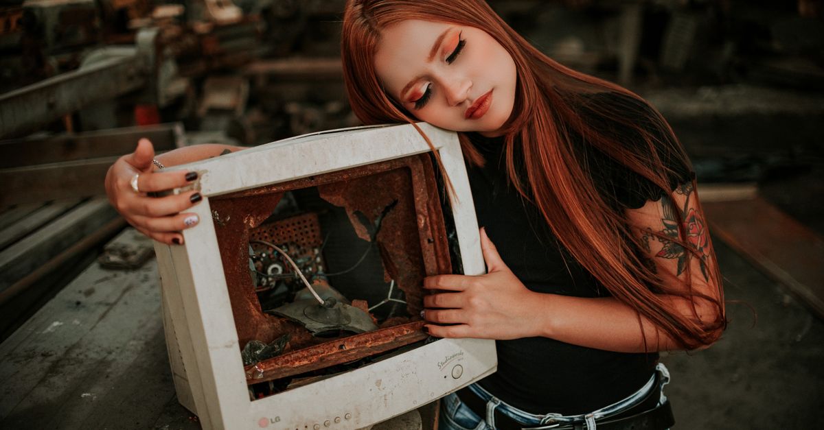 A woman embraces a vintage broken monitor, evoking nostalgia and style.