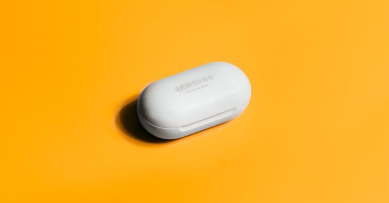 White Samsung wireless earbuds case on a bright yellow background, showcasing sleek tech design.