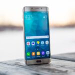 Samsung smartphone placed on a wooden surface outdoors during sunset.