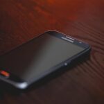 Close-up of a smartphone placed on a dark wooden surface, creating a moody tech ambiance.
