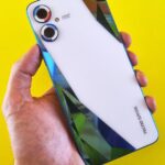 Close-up of a smartphone held in hand against a vibrant yellow background, showcasing modern design.