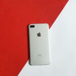A silver smartphone placed on a contrasting red and white background captured from above.